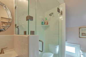 Bathroom featuring toilet, lofted ceiling, and an enclosed shower