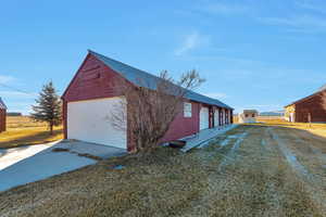 View of property exterior with a lawn, an outdoor structure, and a garage