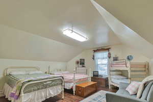 Bedroom featuring dark wood-type flooring and lofted ceiling