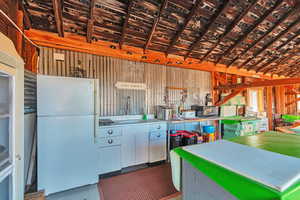 Kitchen with wood walls, sink, lofted ceiling, and white fridge