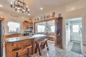 Kitchen with decorative light fixtures, a notable chandelier, stone counters, sink, and stainless steel appliances