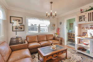 Living room with an inviting chandelier and ornamental molding