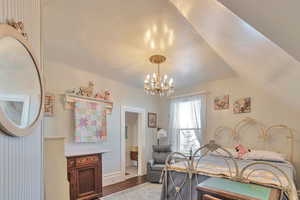 Bedroom with vaulted ceiling, a notable chandelier, and hardwood / wood-style flooring