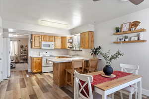 Kitchen with white appliances, sink, a kitchen breakfast bar, kitchen peninsula, and light wood-type flooring