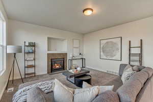 Living room featuring carpet floors and a tiled fireplace