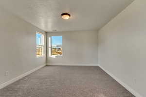 Carpeted empty room featuring a textured ceiling