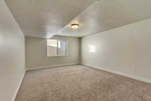 Empty room featuring a textured ceiling and light carpet