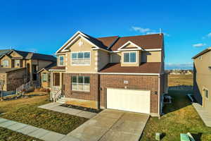 View of front of property with a garage, a front yard, and central AC