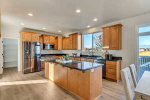 Kitchen with light wood-type flooring, sink, stainless steel appliances, and a kitchen island