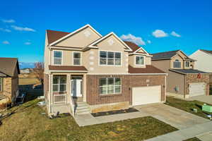 Townhome / multi-family property with a front yard, a porch, a garage, and central AC