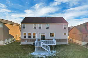 Rear view of house with a deck and a yard