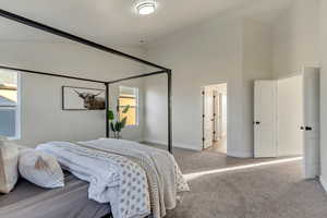 Bedroom with light colored carpet and high vaulted ceiling