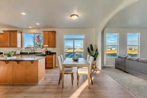 Kitchen featuring a healthy amount of sunlight, sink, a water view, light wood-type flooring, and a breakfast bar