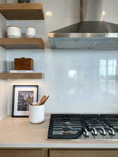 Interior details featuring stainless steel gas cooktop, wall chimney exhaust hood, and tasteful backsplash