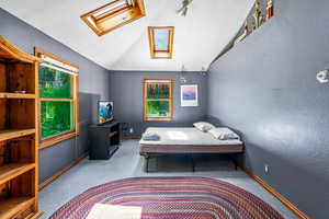 Bedroom featuring carpet, lofted ceiling with skylight, and multiple windows