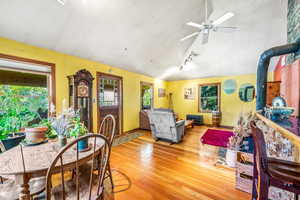 Living room featuring ceiling fan, light wood-type flooring, vaulted ceiling, and a wood stove