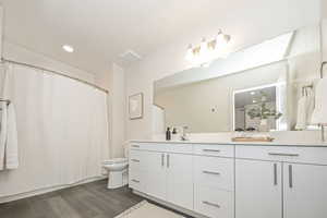 Bathroom featuring toilet, wood-type flooring, and vanity