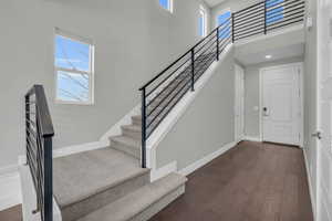 Foyer entrance with dark hardwood / wood-style flooring and a towering ceiling