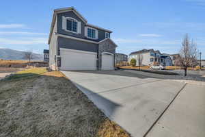 View of front of home with a garage, a front lawn, and a mountain view