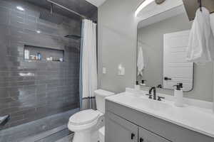 Bathroom with toilet, vanity, and a shower with shower curtain