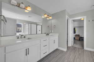 Bathroom featuring a shower with shower door and vanity