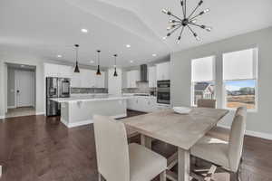 Dining room featuring vaulted ceiling, dark hardwood / wood-style flooring, sink, and a chandelier