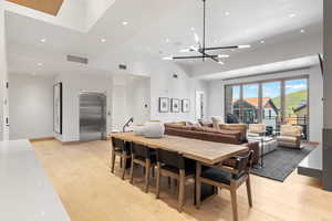 Dining area with a high ceiling, elevator, light hardwood / wood-style flooring, and a notable chandelier