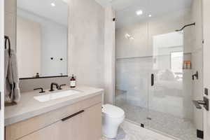 Bathroom with toilet, tile walls, walk in shower, and vanity