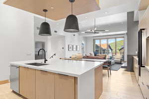 Kitchen featuring decorative light fixtures, a spacious island, sink, light brown cabinets, and a chandelier