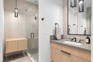 Bathroom with tile patterned flooring, a shower with shower door, tasteful backsplash, and vanity