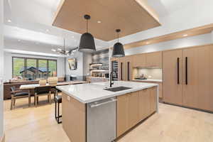 Kitchen featuring a spacious island, pendant lighting, stainless steel dishwasher, sink, and a chandelier