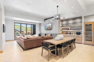 Dining room with light hardwood / wood-style floors, bar, and wine cooler