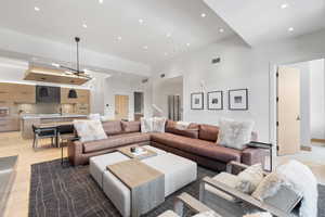 Living room featuring light wood-type flooring, a chandelier, a towering ceiling, and sink