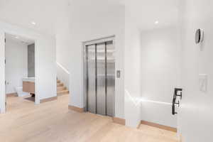 Foyer entrance with light hardwood / wood-style floors and elevator