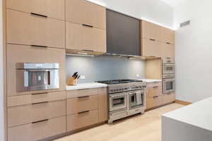 Kitchen with light wood-type flooring, wall chimney exhaust hood, light brown cabinets, and stainless steel appliances