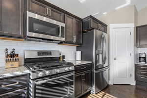 Kitchen with dark brown cabinetry, stainless steel appliances, and tasteful backsplash