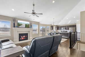 Living room featuring lofted ceiling and ceiling fan with notable chandelier