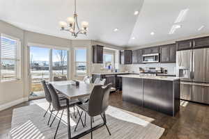 Dining room with lofted ceiling, a notable chandelier, sink, and dark hardwood / wood-style floors