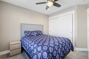 Bedroom with ceiling fan, a closet, and carpet floors