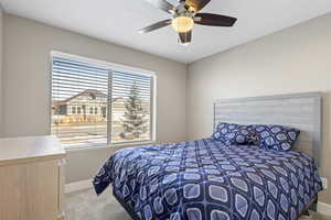 Bedroom with ceiling fan and light carpet