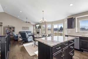 Kitchen featuring light stone countertops, pendant lighting, a center island, backsplash, and stainless steel dishwasher