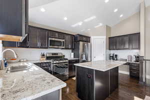 Kitchen with stainless steel appliances, backsplash, a kitchen island, and sink