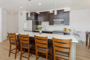 Kitchen featuring decorative light fixtures, stove, white refrigerator, and a breakfast bar area