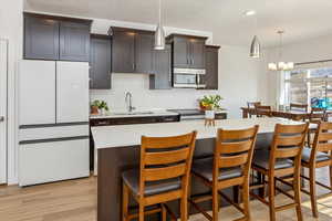 Kitchen featuring dark brown cabinetry, a center island, sink, a chandelier, and a breakfast bar