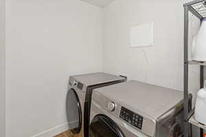 Clothes washing area featuring washer and clothes dryer and light hardwood / wood-style floors