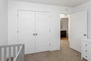 Unfurnished bedroom featuring light colored carpet and a closet