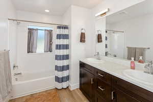 Bathroom with vanity, shower / tub combo with curtain, and hardwood / wood-style floors