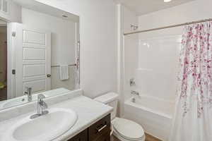 Full bathroom with toilet, hardwood / wood-style floors, vanity, and shower / tub combo with curtain