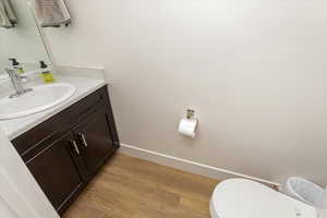 Bathroom with hardwood / wood-style flooring, toilet, and vanity