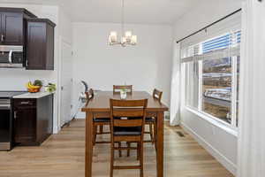 Dining area with light hardwood / wood-style floors and an inviting chandelier